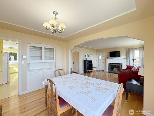 13151/2 W 5th St, Port Angeles, WA 98363 - dining space with arched walkways, a chandelier, light wood-style floors, a fireplace, and baseboards