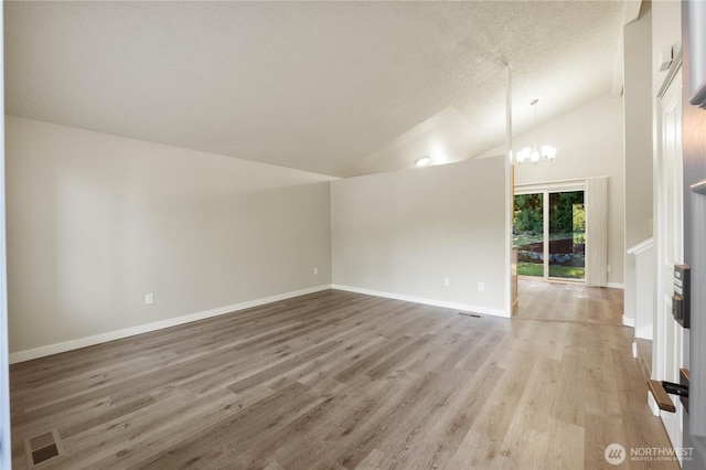 30117 42nd Pl S, Auburn, WA 98001 - unfurnished living room with lofted ceiling, a chandelier, light wood finished floors, baseboards, and a textured ceiling