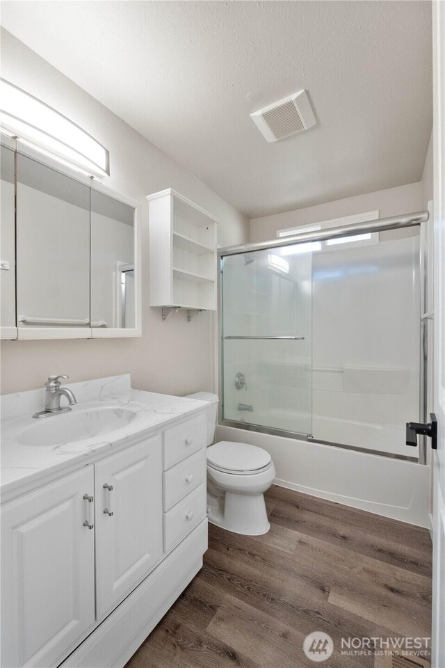 30117 42nd Pl S, Auburn, WA 98001 - bathroom with wood finished floors, vanity, combined bath / shower with glass door, toilet, and a textured ceiling