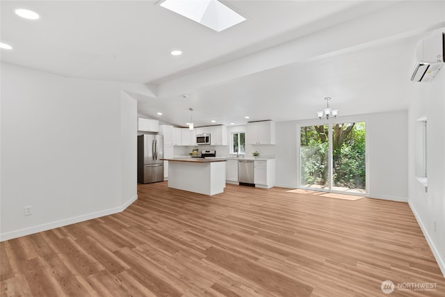 29722 State Highway 3 NE, Poulsbo, WA 98370 - unfurnished living room with a wall unit AC, light wood-type flooring, recessed lighting, a skylight, and baseboards