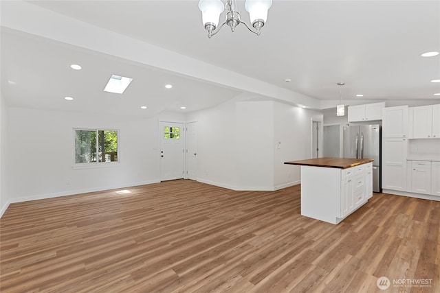 29722 State Highway 3 NE, Poulsbo, WA 98370 - unfurnished living room with light wood-style flooring, recessed lighting, baseboards, a chandelier, and a skylight