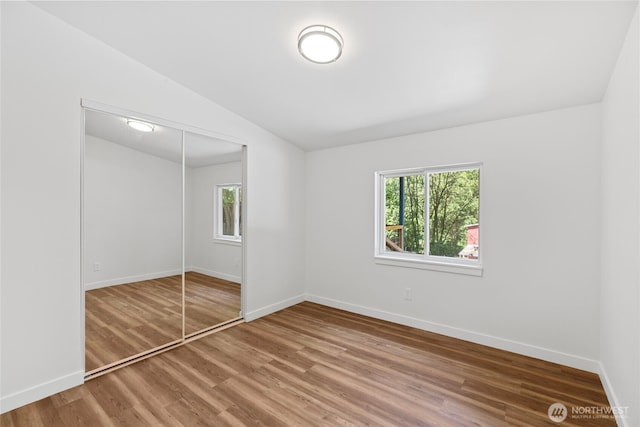29722 State Highway 3 NE, Poulsbo, WA 98370 - unfurnished bedroom with multiple windows, lofted ceiling, wood finished floors, a closet, and baseboards