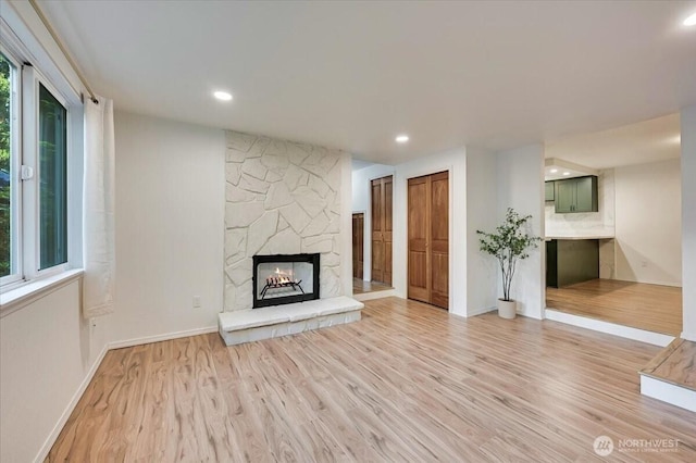 12712 NE 120th St Unit G1, Kirkland, WA 98034 - unfurnished living room with light wood-style flooring, a fireplace, baseboards, and recessed lighting