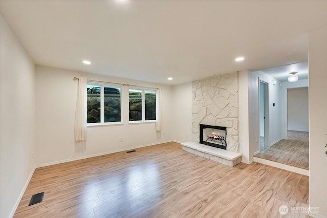 12712 NE 120th St Unit G1, Kirkland, WA 98034 - unfurnished living room featuring wood finished floors, a stone fireplace, baseboards, and recessed lighting