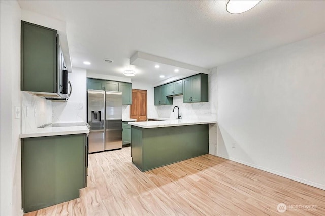 12712 NE 120th St Unit G1, Kirkland, WA 98034 - kitchen featuring appliances with stainless steel finishes, green cabinetry, a peninsula, a sink, and light countertops