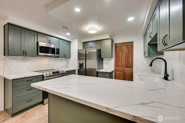 12712 NE 120th St Unit G1, Kirkland, WA 98034 - kitchen with stainless steel appliances, a sink, a peninsula, light stone counters, and backsplash