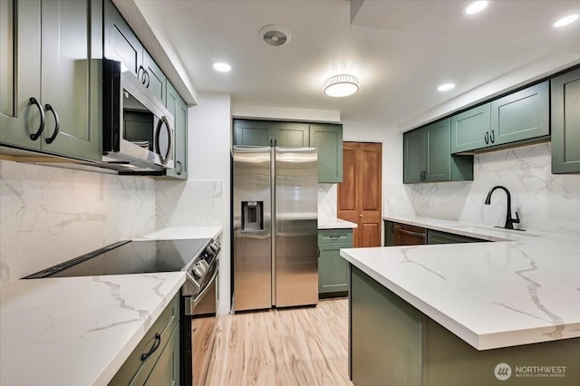 12712 NE 120th St Unit G1, Kirkland, WA 98034 - kitchen featuring stainless steel appliances, green cabinets, a sink, light stone countertops, and decorative backsplash