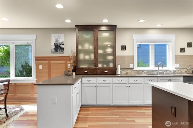 1605 Donovan Ave, Bellingham, WA 98225 - kitchen with light wood-style floors, a peninsula, white cabinetry, glass insert cabinets, and recessed lighting