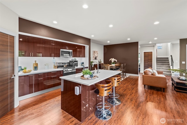 32867 Madrona Ave SE, Black Diamond, WA 98010 - kitchen with modern cabinets, stainless steel appliances, a kitchen breakfast bar, light wood-type flooring, and recessed lighting