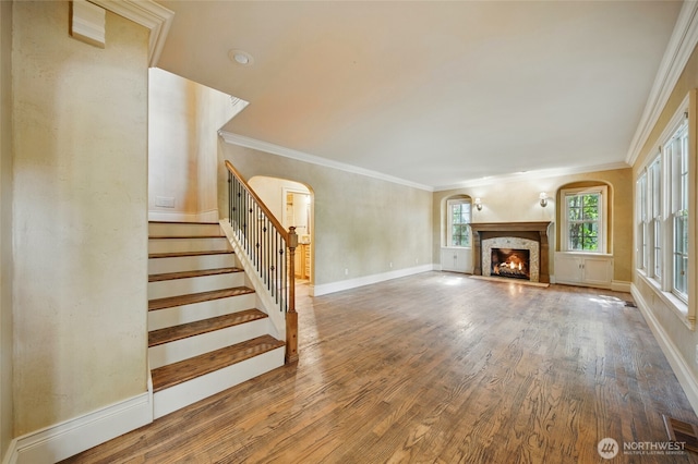 1126 E Alder St, Walla Walla, WA 99362 - unfurnished living room with arched walkways, wood finished floors, stairs, a lit fireplace, and ornamental molding