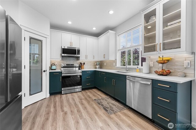 15315 91st Ave SE, Yelm, WA 98597 - kitchen with stainless steel appliances, light wood-type flooring, white cabinets, light countertops, and glass insert cabinets
