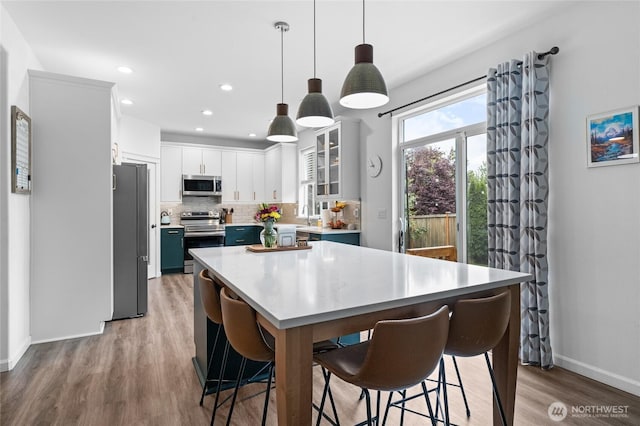 15315 91st Ave SE, Yelm, WA 98597 - kitchen with appliances with stainless steel finishes, light wood finished floors, a breakfast bar area, backsplash, and light countertops