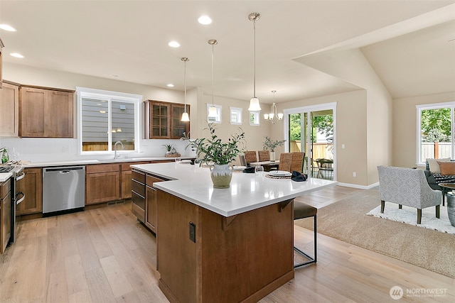 7391 Mirasett St SW Lot 42, Tumwater, WA 98512 - kitchen with stainless steel dishwasher, a breakfast bar, light wood-style flooring, an island with sink, and brown cabinetry
