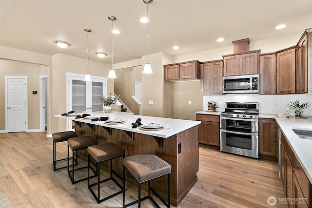 7391 Mirasett St SW Lot 42, Tumwater, WA 98512 - kitchen featuring appliances with stainless steel finishes, light wood-style flooring, a center island, tasteful backsplash, and light countertops