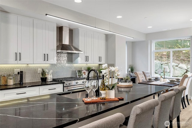 6726 NE 187th St Unit 102, Kenmore, WA 98028 - kitchen with wall chimney exhaust hood, stainless steel gas range, a kitchen breakfast bar, white cabinets, and recessed lighting