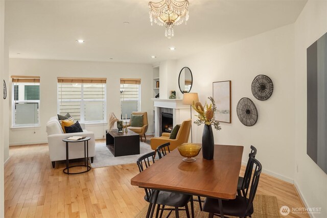 7321 47th Ave SW Unit B, Seattle, WA 98136 - dining area featuring a tile fireplace, light wood-style flooring, recessed lighting, baseboards, and a chandelier