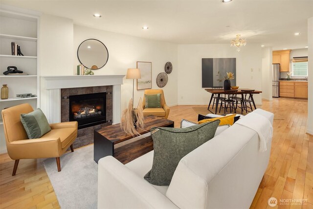 7321 47th Ave SW Unit B, Seattle, WA 98136 - living room featuring light wood finished floors, a tile fireplace, recessed lighting, a chandelier, and baseboards