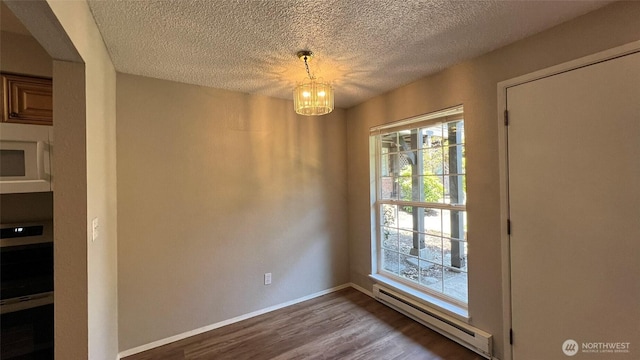 3425 S 176th St Unit 136, Seatac, WA 98188 - unfurnished dining area with a baseboard heating unit, dark wood-type flooring, a chandelier, a textured ceiling, and baseboards