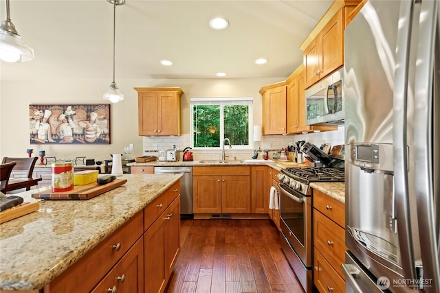 7302 Phillips Rd SE, Port Orchard, WA 98367 - kitchen with stainless steel appliances, a sink, decorative backsplash, dark wood-style floors, and light stone counters