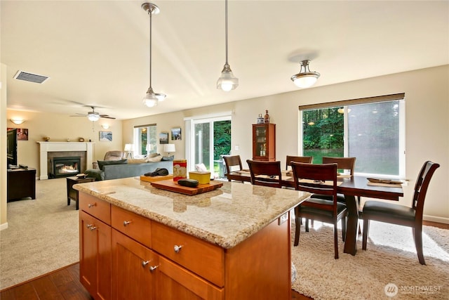 7302 Phillips Rd SE, Port Orchard, WA 98367 - kitchen with dark wood-type flooring, a glass covered fireplace, a center island, light stone countertops, and decorative light fixtures