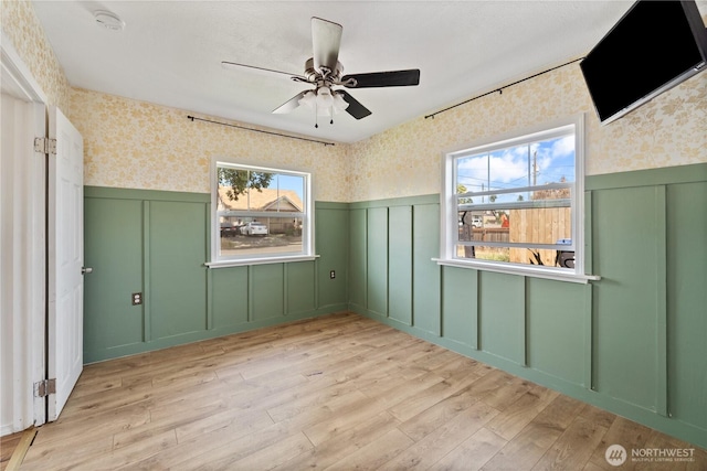1618 Walla Walla Ave, Walla Walla, WA 99362 - unfurnished room featuring wallpapered walls, wainscoting, a decorative wall, light wood-style floors, and a ceiling fan