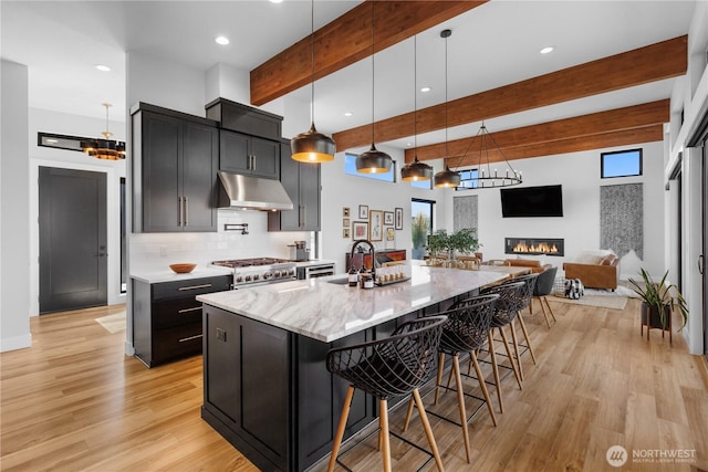 204 Moon River Vw SW, Mattawa, WA 99349 - kitchen featuring under cabinet range hood, beam ceiling, a chandelier, decorative backsplash, and a kitchen bar
