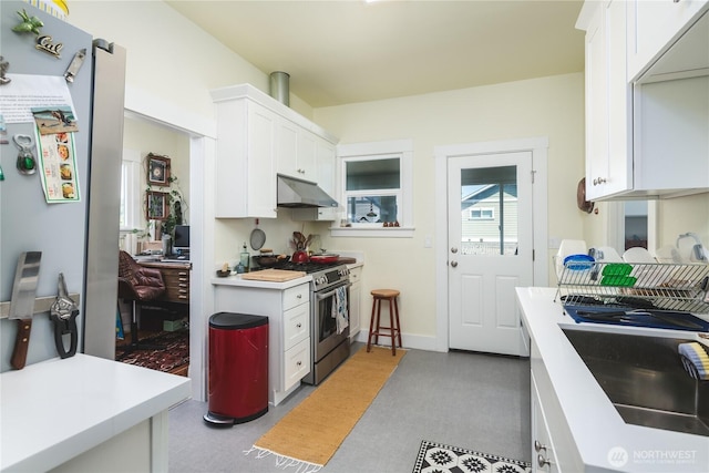 1612 7th St, Anacortes, WA 98221 - kitchen with under cabinet range hood, gas stove, light countertops, white cabinetry, and a sink