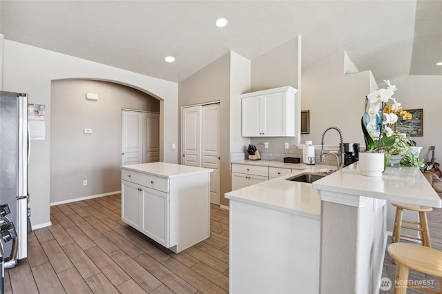 7186 16th Rd NE, Moses Lake, WA 98837 - kitchen featuring freestanding refrigerator, a sink, arched walkways, a peninsula, and wood finish floors