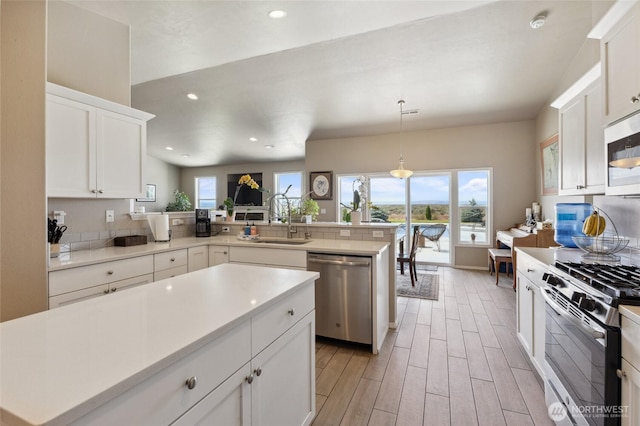 7186 16th Rd NE, Moses Lake, WA 98837 - kitchen with appliances with stainless steel finishes, a sink, a peninsula, light wood finished floors, and white cabinets