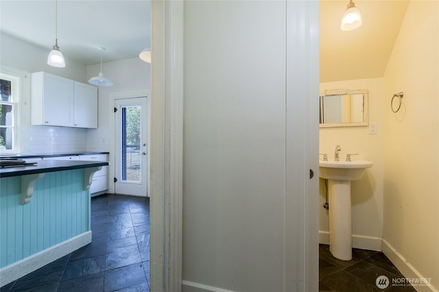 244 Marcus St, Walla Walla, WA 99362 - kitchen featuring a kitchen bar, stone tile floors, white cabinetry, dark countertops, and tasteful backsplash