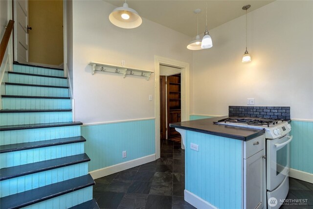 244 Marcus St, Walla Walla, WA 99362 - kitchen featuring white gas stove, wainscoting, dark countertops, hanging light fixtures, and wooden walls