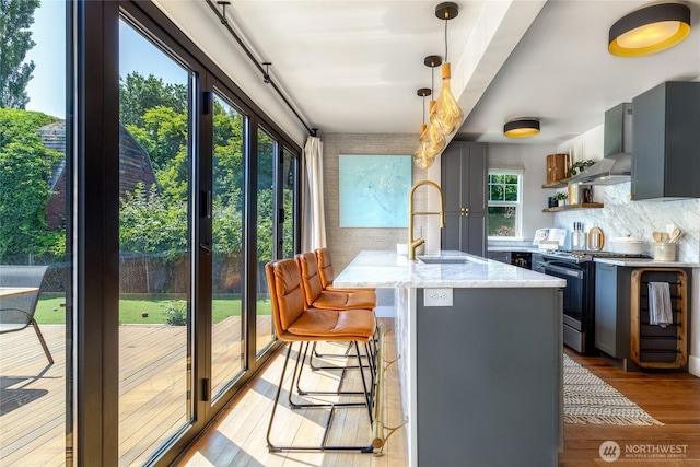 515 S Division St, Walla Walla, WA 99362 - kitchen with electric range, wall chimney exhaust hood, tasteful backsplash, light wood-style floors, and a breakfast bar