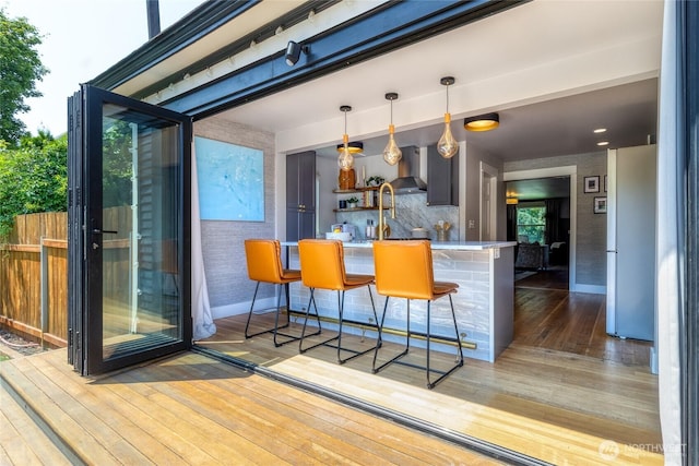 515 S Division St, Walla Walla, WA 99362 - kitchen featuring wall chimney exhaust hood, hardwood / wood-style flooring, freestanding refrigerator, a breakfast bar, and decorative light fixtures