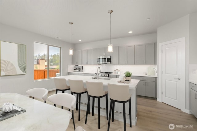 13307 SE 238th Pl Unit 11, Kent, WA 98042 - kitchen with stainless steel microwave, gray cabinetry, a sink, a breakfast bar area, and an island with sink