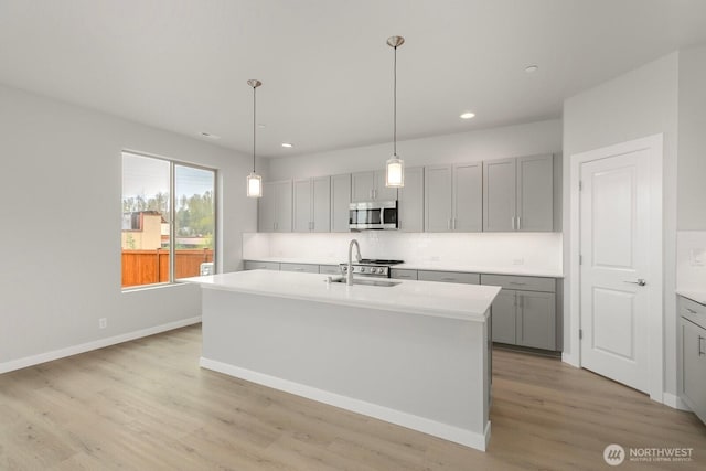 13307 SE 238th Pl Unit 11, Kent, WA 98042 - kitchen featuring stainless steel microwave, a sink, gray cabinetry, backsplash, and light wood-type flooring