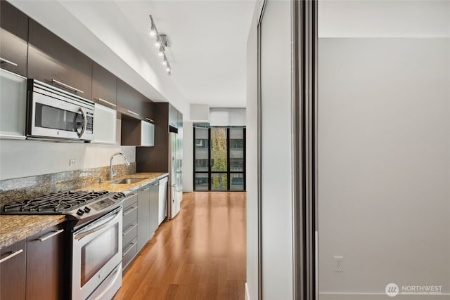 2911 2nd Ave Unit 522, Seattle, WA 98121 - kitchen featuring stainless steel appliances, a sink, modern cabinets, light wood-style floors, and light stone counters