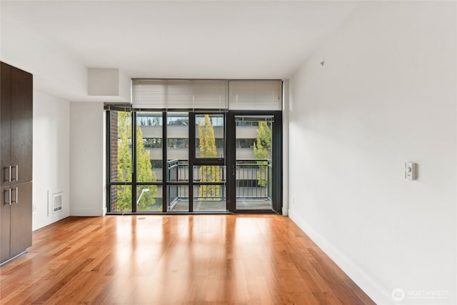 2911 2nd Ave Unit 522, Seattle, WA 98121 - unfurnished room with plenty of natural light, light wood-style flooring, baseboards, and expansive windows