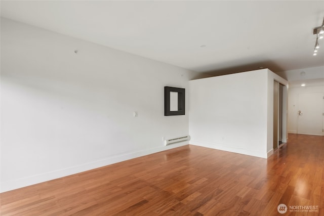 2911 2nd Ave Unit 522, Seattle, WA 98121 - unfurnished room with baseboard heating, wood finished floors, and baseboards