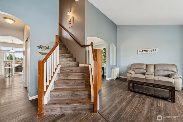 10089 Jensen Dr SE, Yelm, WA 98597 - stairs with arched walkways, wood finished floors, and a towering ceiling