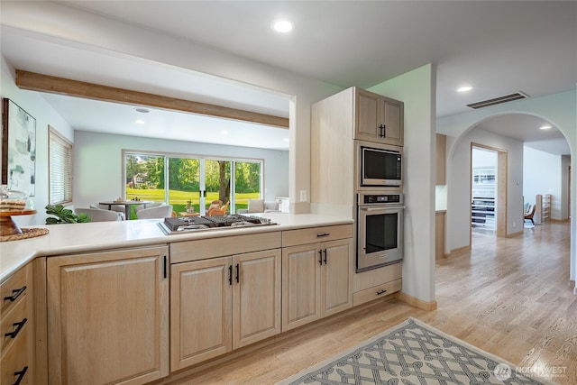5520 Canvasback Rd, Blaine, WA 98230 - kitchen with appliances with stainless steel finishes, light brown cabinetry, light wood-style flooring, arched walkways, and light countertops