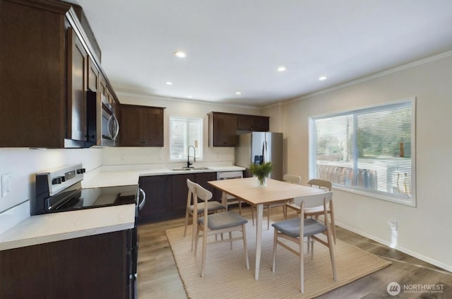 704 N 3rd St, Westport, WA 98595 - kitchen with appliances with stainless steel finishes, dark brown cabinets, crown molding, recessed lighting, and light countertops