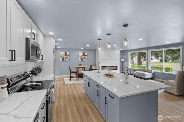 18604 9th Avenue Ct E, Spanaway, WA 98387 - kitchen with appliances with stainless steel finishes, open floor plan, recessed lighting, a fireplace, and light wood finished floors