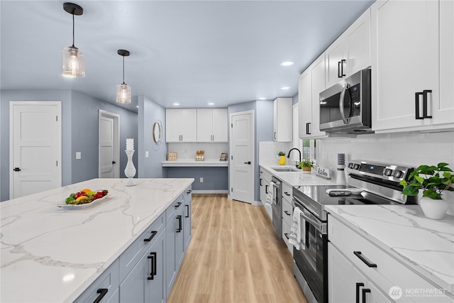 18604 9th Avenue Ct E, Spanaway, WA 98387 - kitchen with stainless steel appliances, light wood-style floors, white cabinetry, decorative light fixtures, and decorative backsplash