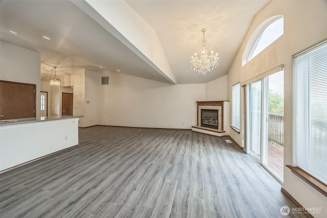 5 Bayview Ln, Hoquiam, WA 98550 - unfurnished living room with a chandelier, wood finished floors, high vaulted ceiling, a tile fireplace, and baseboards