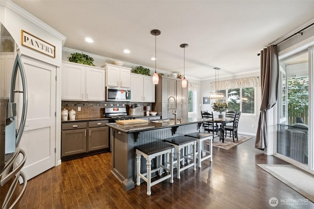 19409 90th Avenue Ct E, Graham, WA 98338 - kitchen with appliances with stainless steel finishes, dark countertops, ornamental molding, dark wood-style floors, and a breakfast bar