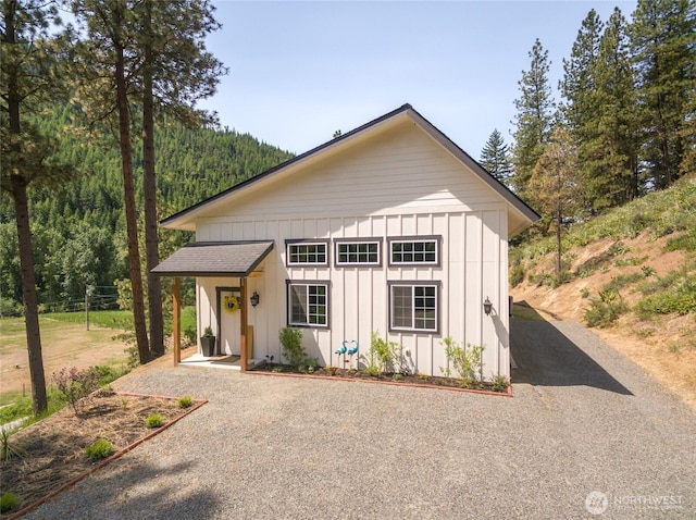 10642 Merry Canyon Rd, Leavenworth, WA 98820 - view of front facade featuring board and batten siding, an outbuilding, and a forest view