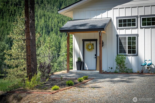 10642 Merry Canyon Rd, Leavenworth, WA 98820 - entrance to property with board and batten siding, a view of trees, and a shingled roof