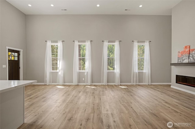 10642 Merry Canyon Rd, Leavenworth, WA 98820 - unfurnished living room featuring light wood finished floors, a glass covered fireplace, baseboards, and recessed lighting