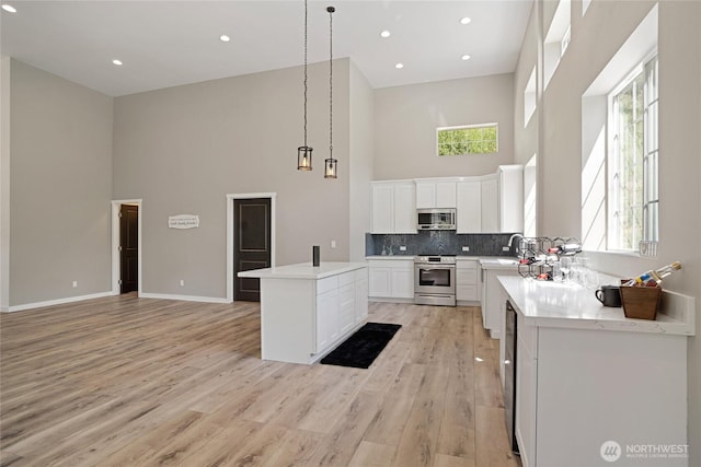 10642 Merry Canyon Rd, Leavenworth, WA 98820 - kitchen featuring appliances with stainless steel finishes, a towering ceiling, a kitchen island, light wood-style floors, and a sink