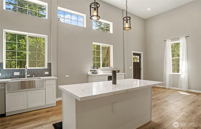 10642 Merry Canyon Rd, Leavenworth, WA 98820 - kitchen featuring a sink, a towering ceiling, light wood-style flooring, decorative light fixtures, and light stone countertops